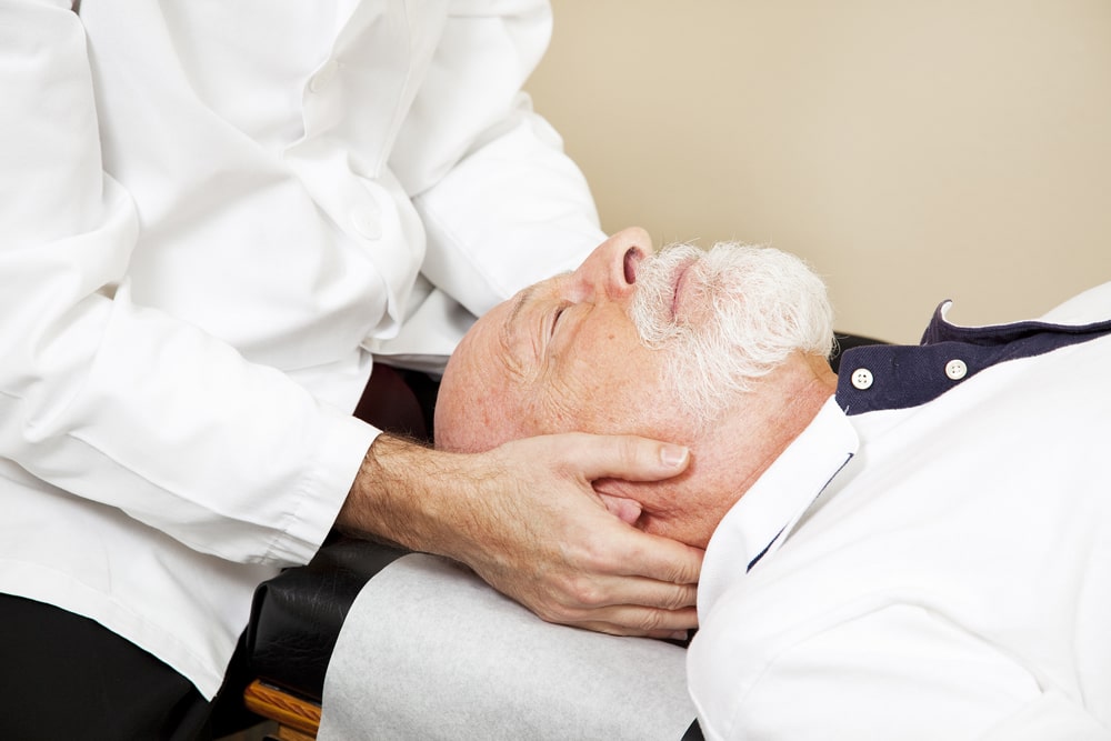 male patient laying down and receiving chiropractic treatment for his neck pain